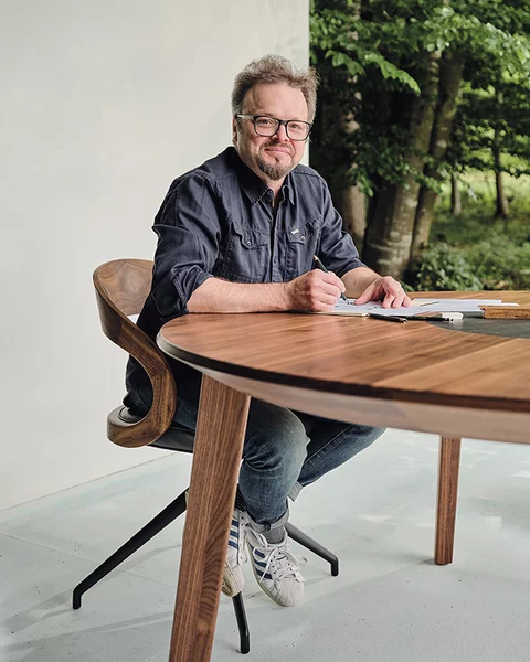 Sebastian Desch with the miró dining table in walnut Designer Sebastian Desch with the self-designed miró dining table in walnut