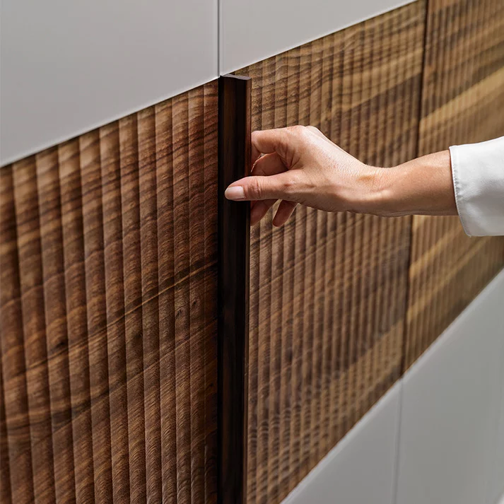 Drehtürenschrank Holzband Relief aus Holz mit Farbglasfronten, Detailansicht valore Drehtürenschrank Holzband Relief in Nussbaum mit Farbglasfronten, Detailansicht